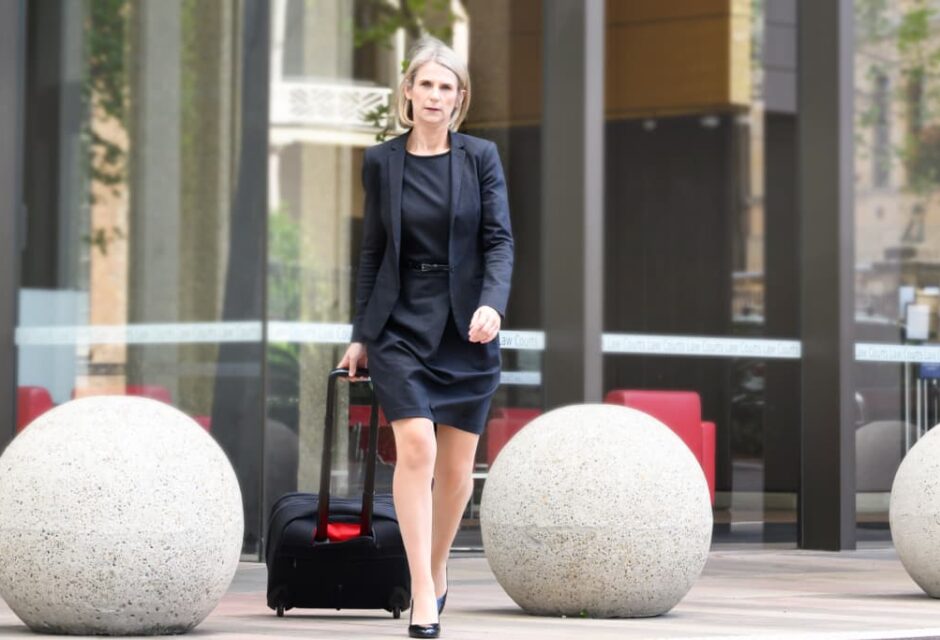 Helen Roebuck walking out of Sydney Law Courts, with a wheeled brief case
